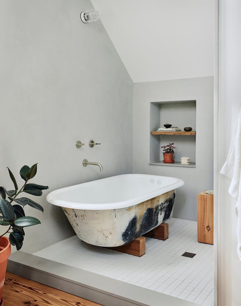 A banheira com um design único é colocada no chão de ladrilhos brancos