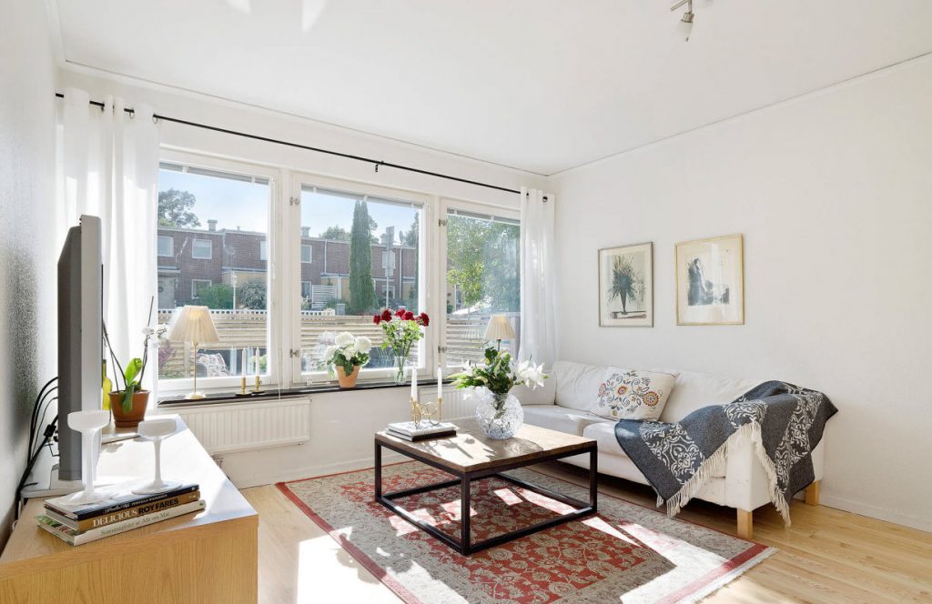 Další pohled na obývací pokoj s velkými okny a bílými závěsy a krásnými dekoracemi