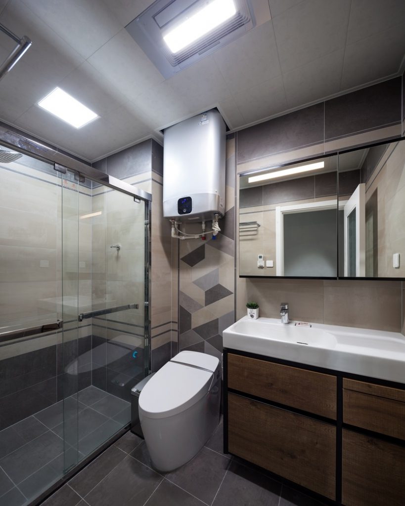 Kamar mandi bersama ditutupi dengan ubin anti selip, lemari cermin, dinding pancuran kaca, dan peralatan sanitasi modern