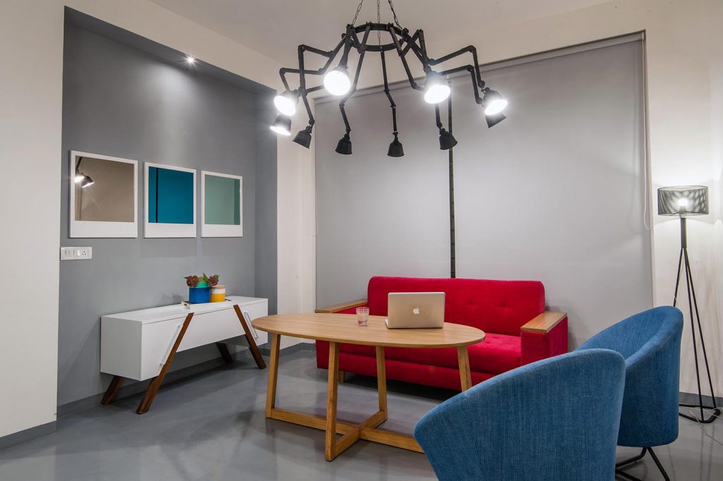 Tavanda bol miktarda ışık alan, çarpıcı mavi ve yeşil masa ve sandalyelere sahip stüdyo oda